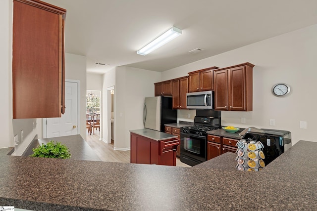 6 Castle Hall Ct, Simpsonville, SC 29681 - kitchen featuring appliances with stainless steel finishes, dark countertops, light wood-style floors, a center island, and a peninsula
