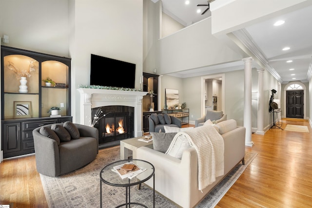 623 N Main St Unit Iii, Unit Iii, Greenville, SC 29601 - living room featuring crown molding, light wood-style flooring, a glass covered fireplace, decorative columns, and a high ceiling