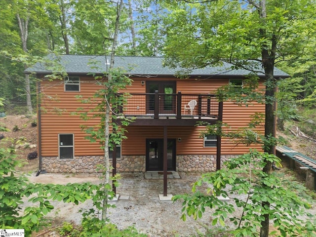 1150 Chinquapin Rd, Travelers Rest, SC 29690 - back of property featuring faux log siding, stone siding, french doors, roof with shingles, and a balcony