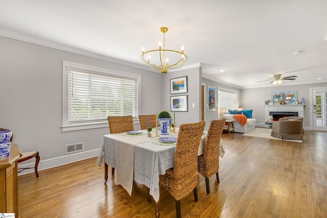 2109 Hudson Rd, Greer, SC 29650 - dining area with crown molding, a chandelier, light wood-type flooring, a ceiling fan, and a lit fireplace