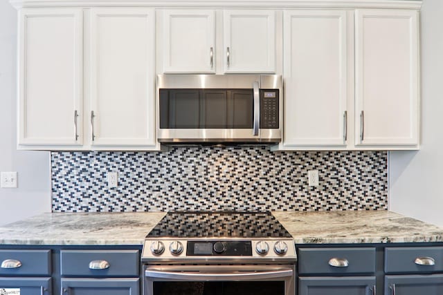 236 Worcester Ln, Easley, SC 29642 - kitchen with appliances with stainless steel finishes, blue cabinetry, tasteful backsplash, light stone counters, and white cabinetry