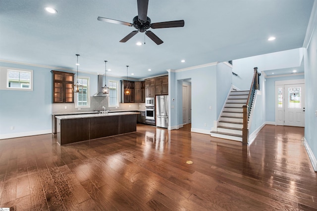 113 River Pines Trl, Greer, SC 29651 - kitchen featuring stainless steel appliances, wall chimney range hood, a kitchen island with sink, dark wood-style floors, and ornamental molding