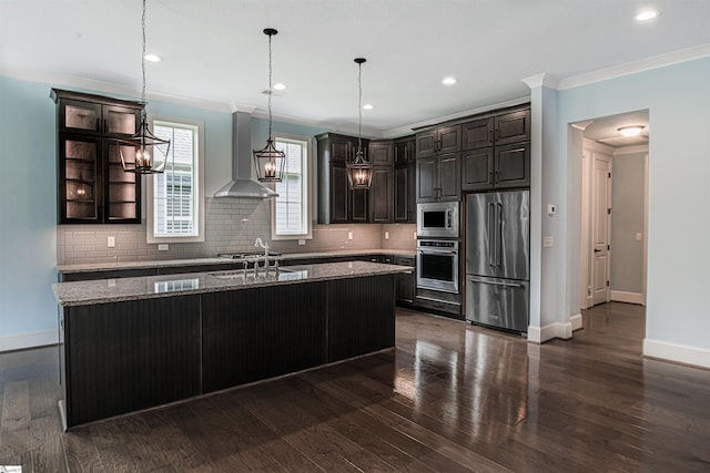 113 River Pines Trl, Greer, SC 29651 - kitchen with stainless steel appliances, wall chimney range hood, light stone countertops, decorative backsplash, and a kitchen island with sink