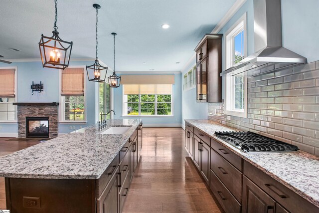 113 River Pines Trl, Greer, SC 29651 - kitchen with wall chimney range hood, stainless steel gas cooktop, dark wood finished floors, dark brown cabinets, and a kitchen island with sink