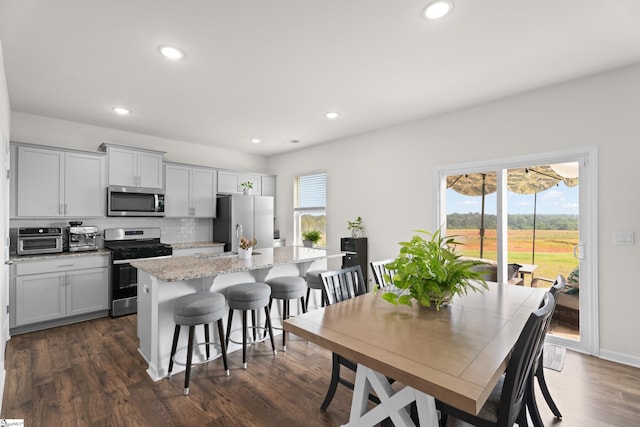 220 Emerald Creek Ave, Greer, SC 29651 - kitchen with appliances with stainless steel finishes, a kitchen island, a kitchen breakfast bar, decorative backsplash, and recessed lighting