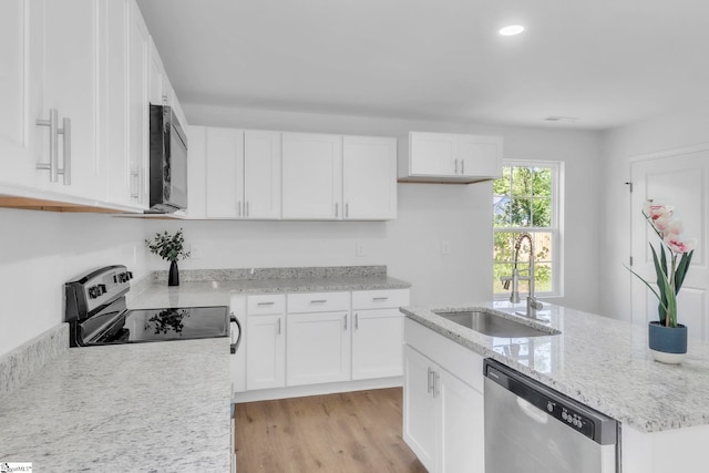 517 Farley Ave, Spartanburg, SC 29301 - kitchen featuring appliances with stainless steel finishes, white cabinetry, light wood-style floors, light stone counters, and a center island with sink