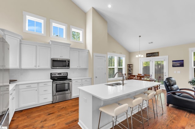 104 Mares Head Pl, Taylors, SC 29687 - kitchen featuring appliances with stainless steel finishes, high vaulted ceiling, wood finished floors, a breakfast bar area, and decorative backsplash