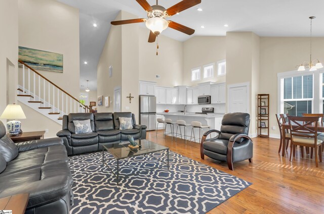 104 Mares Head Pl, Taylors, SC 29687 - living area featuring high vaulted ceiling, light wood-type flooring, ceiling fan, stairs, and a chandelier