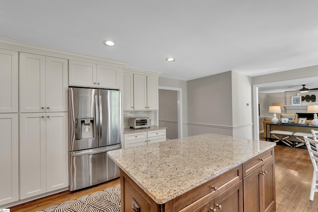 111 Brandon Way, Simpsonville, SC 29681 - kitchen featuring stainless steel fridge, light wood-type flooring, light stone countertops, ceiling fan, and a center island