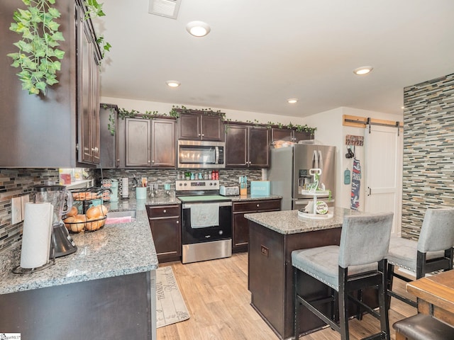 126 Blue Springs Way, Simpsonville, SC 29680 - kitchen featuring stainless steel appliances, dark brown cabinets, backsplash, light wood-type flooring, and a kitchen bar