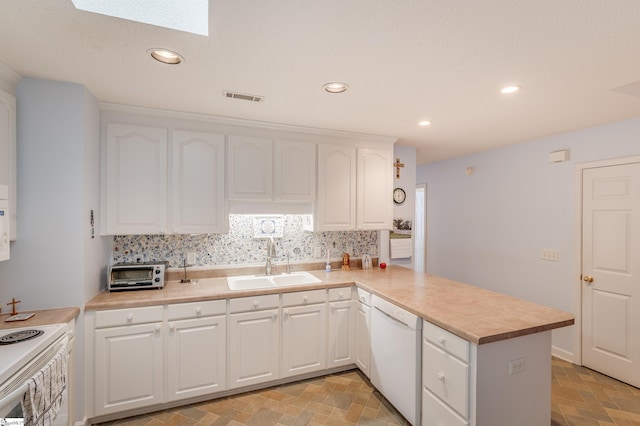 110 Baldwin Pl, Easley, SC 29642 - kitchen featuring white appliances, a peninsula, a skylight, tasteful backsplash, and recessed lighting