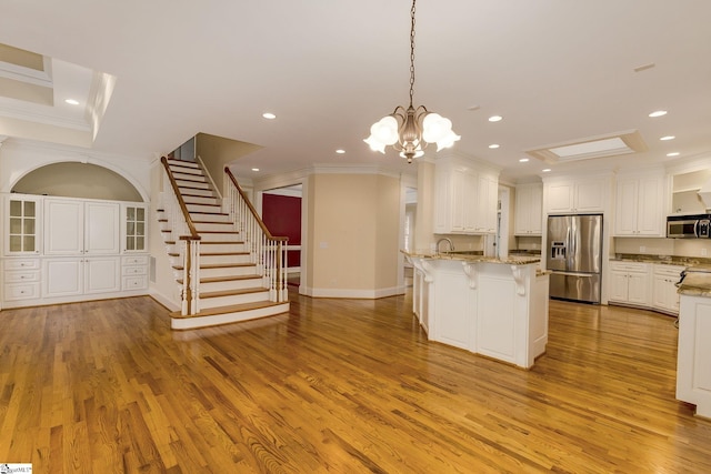 3 Henson Pl, Greer, SC 29650 - kitchen featuring appliances with stainless steel finishes, crown molding, a kitchen bar, light wood finished floors, and light stone counters