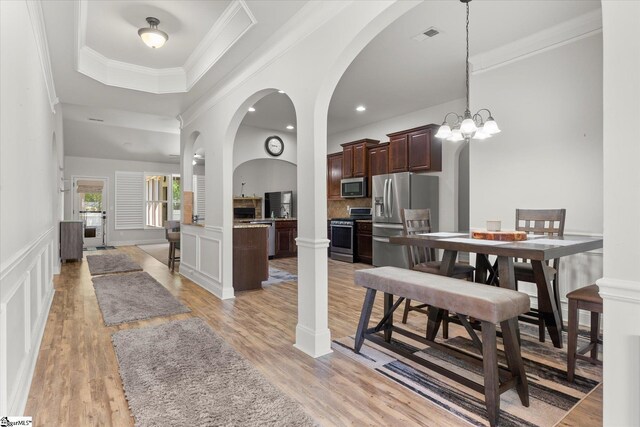 505 E Czardas Way, Woodruff, SC 29375 - dining room with a raised ceiling, light wood-type flooring, ornamental molding, a decorative wall, and arched walkways