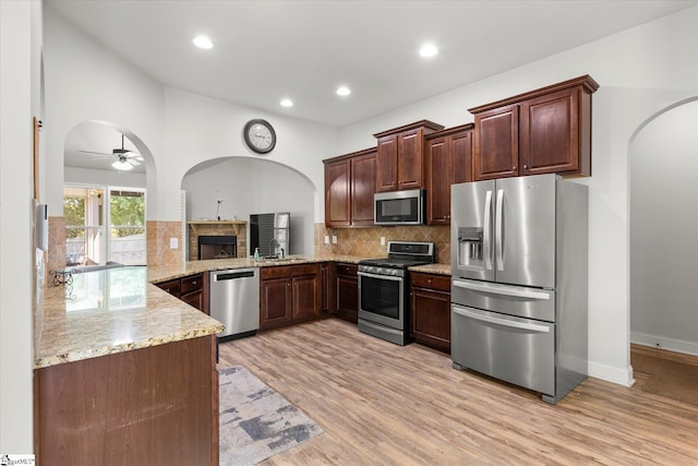 505 E Czardas Way, Woodruff, SC 29375 - kitchen featuring appliances with stainless steel finishes, arched walkways, light stone countertops, ceiling fan, and light wood-style floors