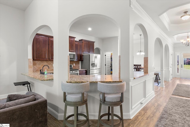 505 E Czardas Way, Woodruff, SC 29375 - kitchen featuring stainless steel appliances, a chandelier, decorative backsplash, a breakfast bar area, and light wood-style flooring