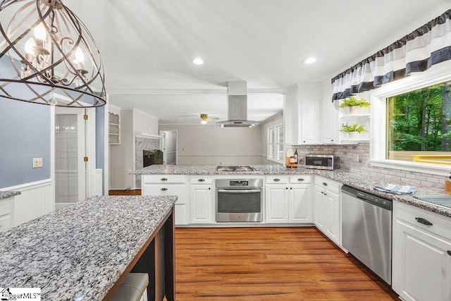 111 Bonwood Ave, Simpsonville, SC 29681 - kitchen with stainless steel appliances, island range hood, light wood-style floors, white cabinetry, and a peninsula