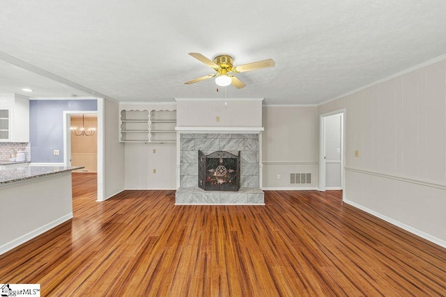 111 Bonwood Ave, Simpsonville, SC 29681 - unfurnished living room with wood finished floors, a ceiling fan, a tiled fireplace, a chandelier, and crown molding