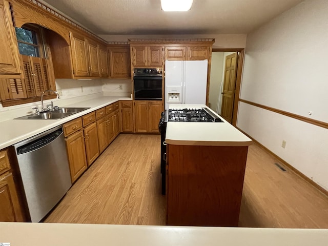 504 N Adair St, Clinton, SC 29325 - kitchen featuring stainless steel appliances, light wood-style flooring, brown cabinetry, and a center island