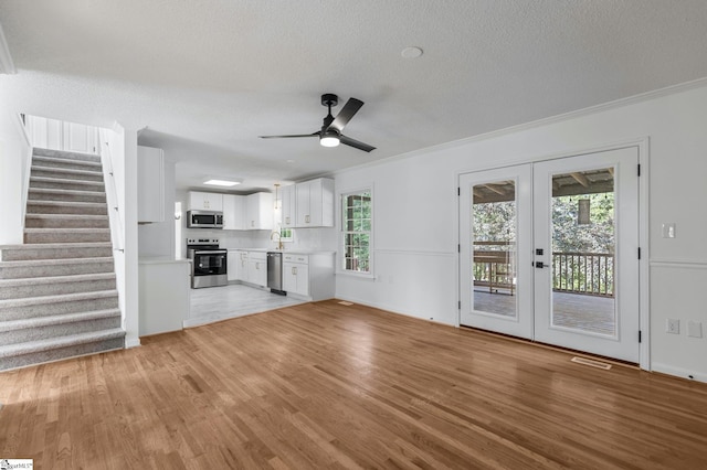 612 Walnut Way, Anderson, SC 29626 - unfurnished living room with light wood-style floors, a textured ceiling, ceiling fan, stairs, and french doors