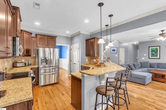 911 Devenger Rd, Greer, SC 29650 - kitchen with appliances with stainless steel finishes, a peninsula, a kitchen breakfast bar, light wood finished floors, and ornamental molding