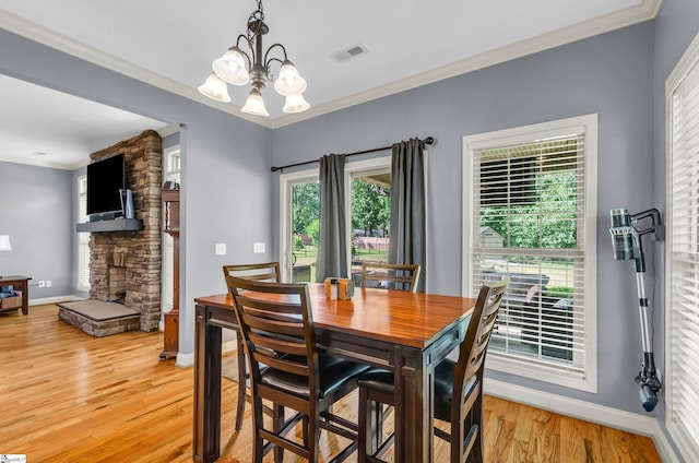 911 Devenger Rd, Greer, SC 29650 - dining space featuring a chandelier, light wood-style floors, crown molding, and a stone fireplace