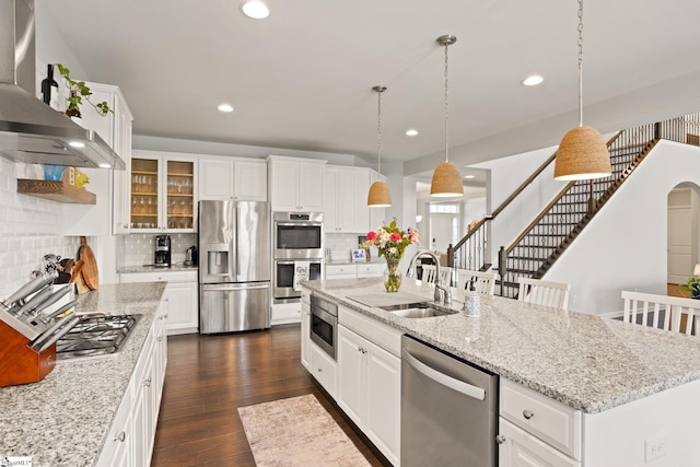 430 Cloverland Ln, Duncan, SC 29334 - kitchen featuring stainless steel appliances, wall chimney range hood, a kitchen island with sink, tasteful backsplash, and glass insert cabinets