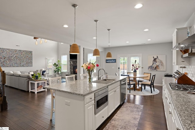 430 Cloverland Ln, Duncan, SC 29334 - kitchen featuring stainless steel appliances, a stone fireplace, white cabinetry, a breakfast bar area, and dark wood-style floors