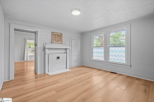 313 S Georgia Ave, Chesnee, SC 29323 - unfurnished living room with light wood-type flooring, crown molding, healthy amount of natural light, and a brick fireplace