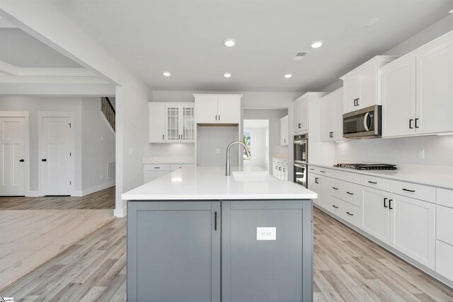 913 Wild Pine Ct, Duncan, SC 29334 - kitchen with appliances with stainless steel finishes, light wood-type flooring, white cabinets, a center island with sink, and light countertops