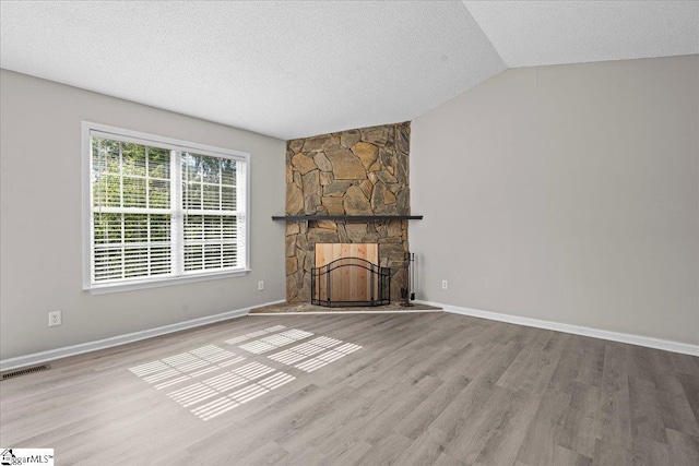 263 Cornelson Dr, Greer, SC 29651 - unfurnished living room with wood finished floors, a stone fireplace, a textured ceiling, and vaulted ceiling