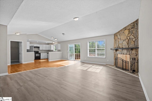 263 Cornelson Dr, Greer, SC 29651 - unfurnished living room with vaulted ceiling, light wood-style flooring, a fireplace, and a textured ceiling