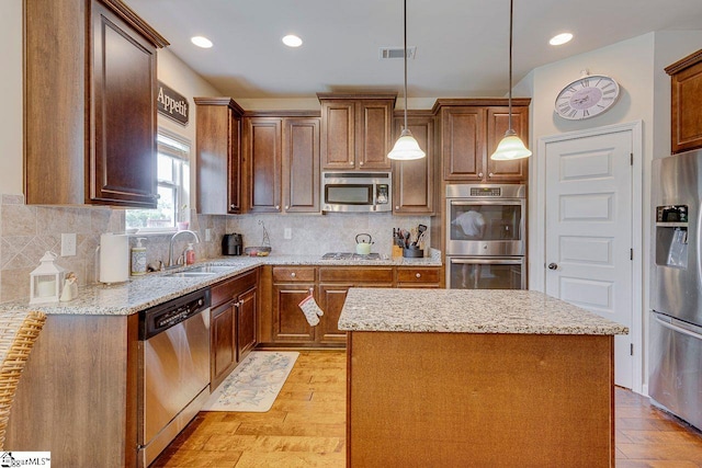 104 Saddlehorn Ln, Easley, SC 29642 - kitchen featuring appliances with stainless steel finishes, light stone counters, a kitchen island, decorative light fixtures, and light wood finished floors