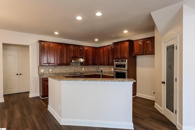 515 Etowah Dr, Roebuck, SC 29376 - kitchen featuring under cabinet range hood, dark wood finished floors, light stone counters, a kitchen island with sink, and recessed lighting