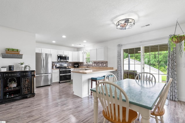 640 Slippery Moss Dr, Spartanburg, SC 29303 - kitchen featuring appliances with stainless steel finishes, a peninsula, wood finished floors, tasteful backsplash, and a textured ceiling
