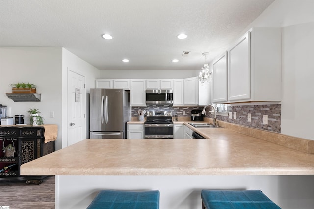 640 Slippery Moss Dr, Spartanburg, SC 29303 - kitchen featuring appliances with stainless steel finishes, a peninsula, light countertops, tasteful backsplash, and white cabinets