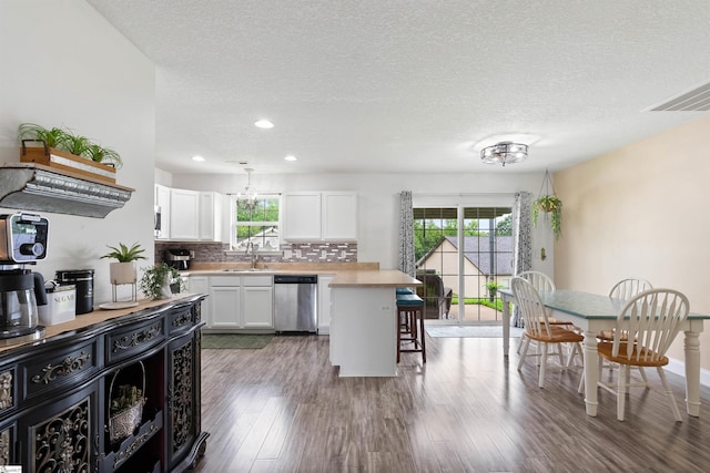 640 Slippery Moss Dr, Spartanburg, SC 29303 - kitchen featuring stainless steel dishwasher, light countertops, white cabinetry, backsplash, and a breakfast bar area