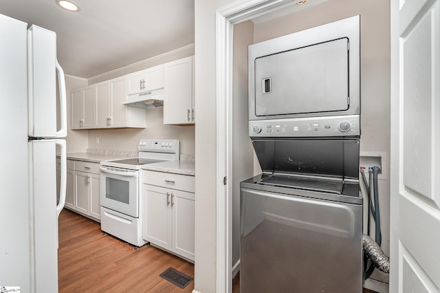 509 Montague St, Anderson, SC 29624 - kitchen featuring white appliances, under cabinet range hood, stacked washing machine and dryer, light wood finished floors, and white cabinetry
