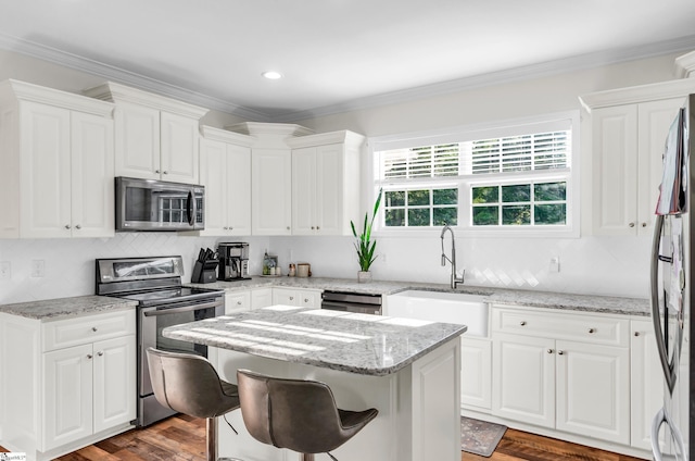 304 Camperdown Ct, Easley, SC 29642 - kitchen featuring appliances with stainless steel finishes, white cabinets, a center island, crown molding, and light stone counters