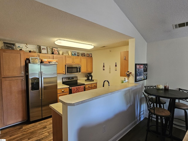 632 Lookover Dr, Anderson, SC 29621 - kitchen with appliances with stainless steel finishes, a textured ceiling, a peninsula, dark wood-type flooring, and light countertops