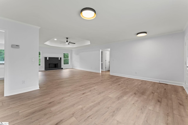 2005 Gap Creek Rd, Greer, SC 29651 - unfurnished living room featuring a ceiling fan, a raised ceiling, crown molding, light wood-style flooring, and a brick fireplace