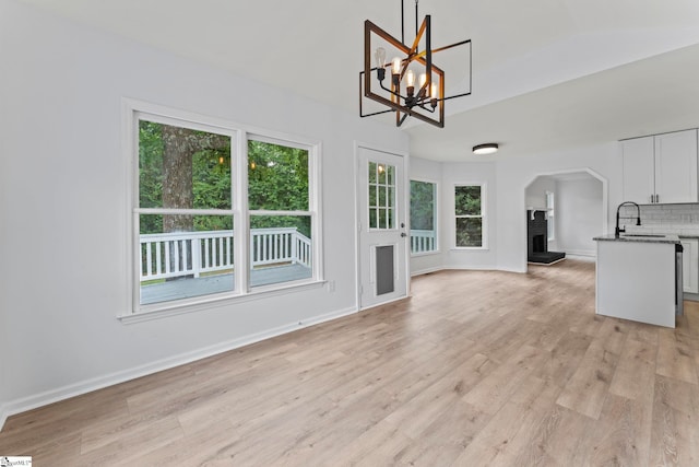2005 Gap Creek Rd, Greer, SC 29651 - unfurnished living room with light wood-style floors, a fireplace, arched walkways, a chandelier, and vaulted ceiling