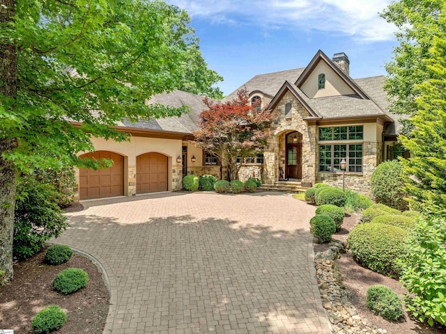 24 Lake Hills Ln, Travelers Rest, SC 29690 - view of front of property featuring stone siding, stucco siding, a chimney, and an attached garage