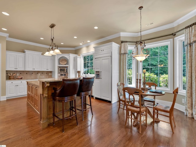 24 Lake Hills Ln, Travelers Rest, SC 29690 - kitchen with appliances with stainless steel finishes, a kitchen island, white cabinetry, decorative backsplash, and ornamental molding