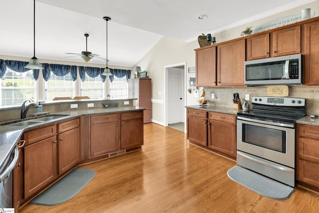 112 Friesian Ct, Pelzer, SC 29669 - kitchen with appliances with stainless steel finishes, brown cabinetry, vaulted ceiling, ceiling fan, and backsplash