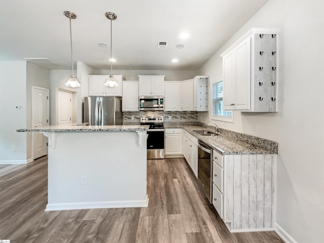 163 Highland Park Ct, Easley, SC 29642 - kitchen featuring stainless steel appliances, wood finished floors, a breakfast bar, white cabinetry, and a kitchen island