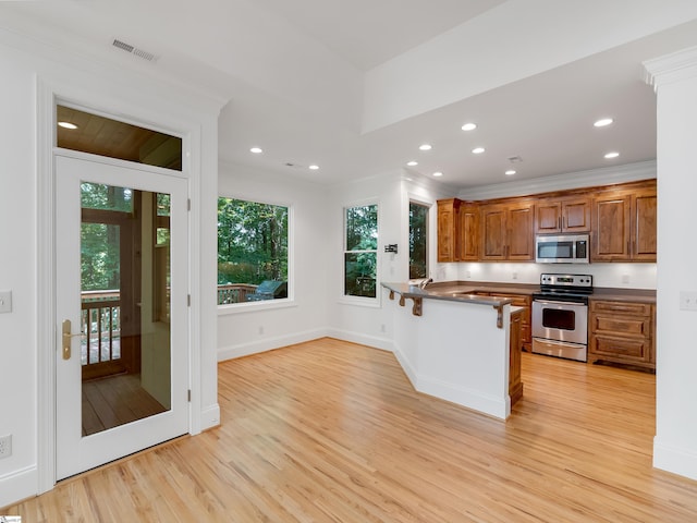 1 Touch Me Not Trl, Landrum, SC 29356 - kitchen with stainless steel appliances, light wood-type flooring, a peninsula, brown cabinetry, and a kitchen bar