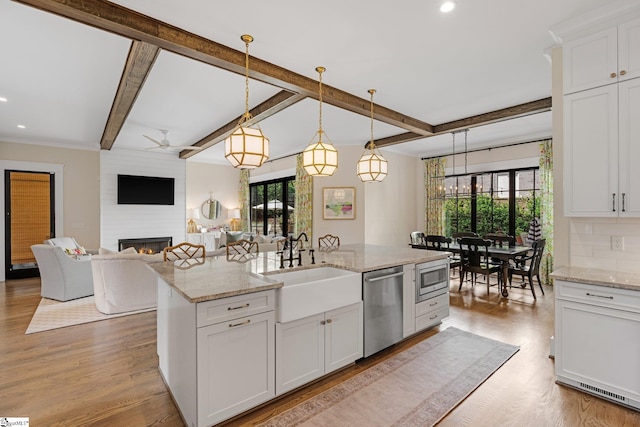 352 Pine Forest Drive Extension, Greenville, SC 29605 - kitchen featuring stainless steel appliances, a large fireplace, beam ceiling, white cabinetry, and a kitchen island with sink