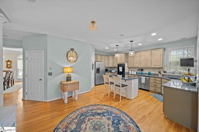 2 Willow Oak Ct, Simpsonville, SC 29681 - kitchen with stainless steel appliances, light brown cabinetry, light wood finished floors, a kitchen bar, and a kitchen island
