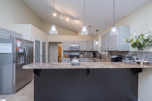 6 Gratiot Ln, Greer, SC 29651 - kitchen featuring stainless steel appliances, vaulted ceiling, a peninsula, decorative backsplash, and light stone countertops