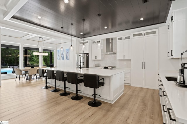 421 Lynn Rd, Taylors, SC 29687 - kitchen with wall chimney exhaust hood, stainless steel fridge with ice dispenser, a breakfast bar area, light wood-type flooring, and light countertops